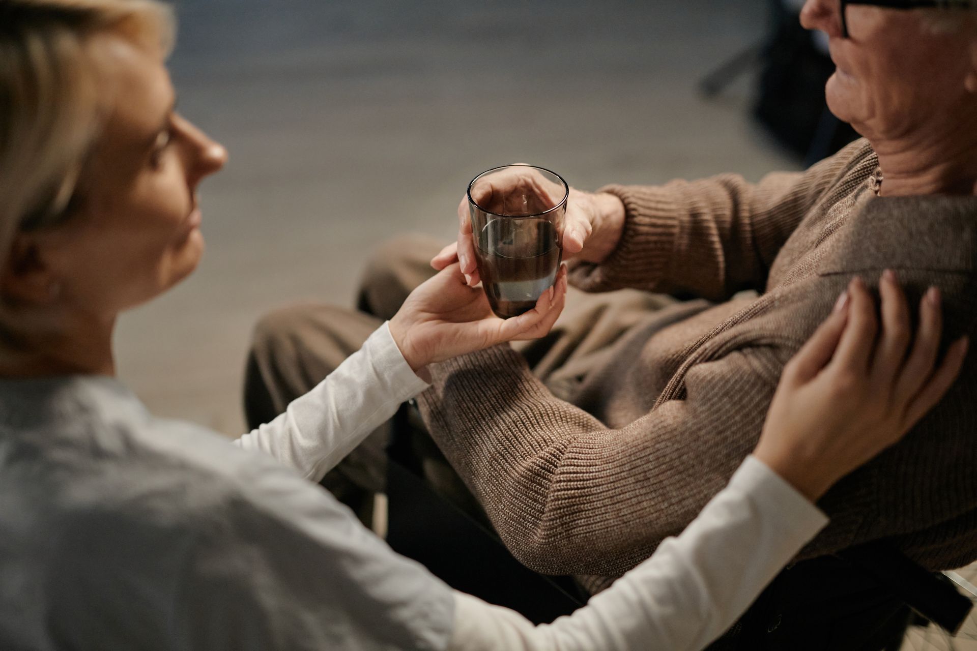 Caregiver offering a glass of water to an elderly man at home in San Diego CA Caregiver offering a glass of water to an elderly man at home in San Diego CA
