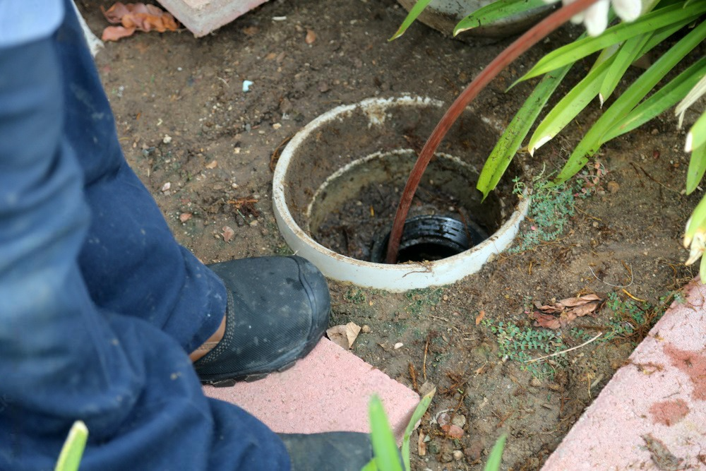 A person is working on a drain in the ground.