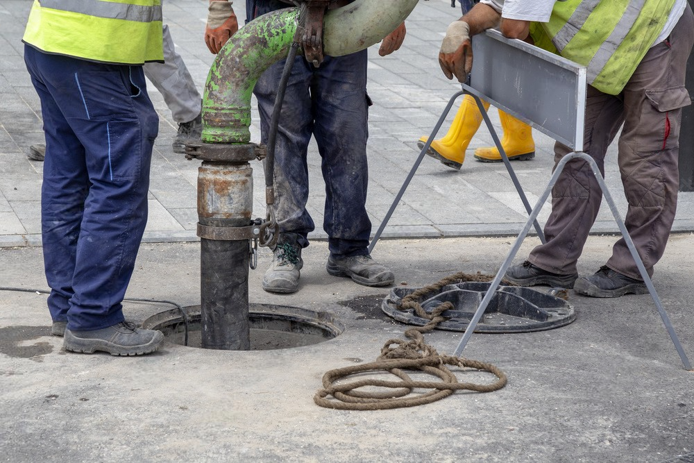 A group of men are working on a manhole cover.