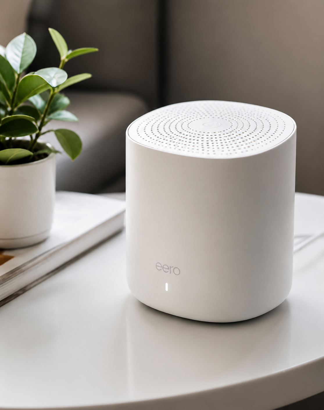 White cylindrical air purifier on a white table beside a potted plant in a modern room