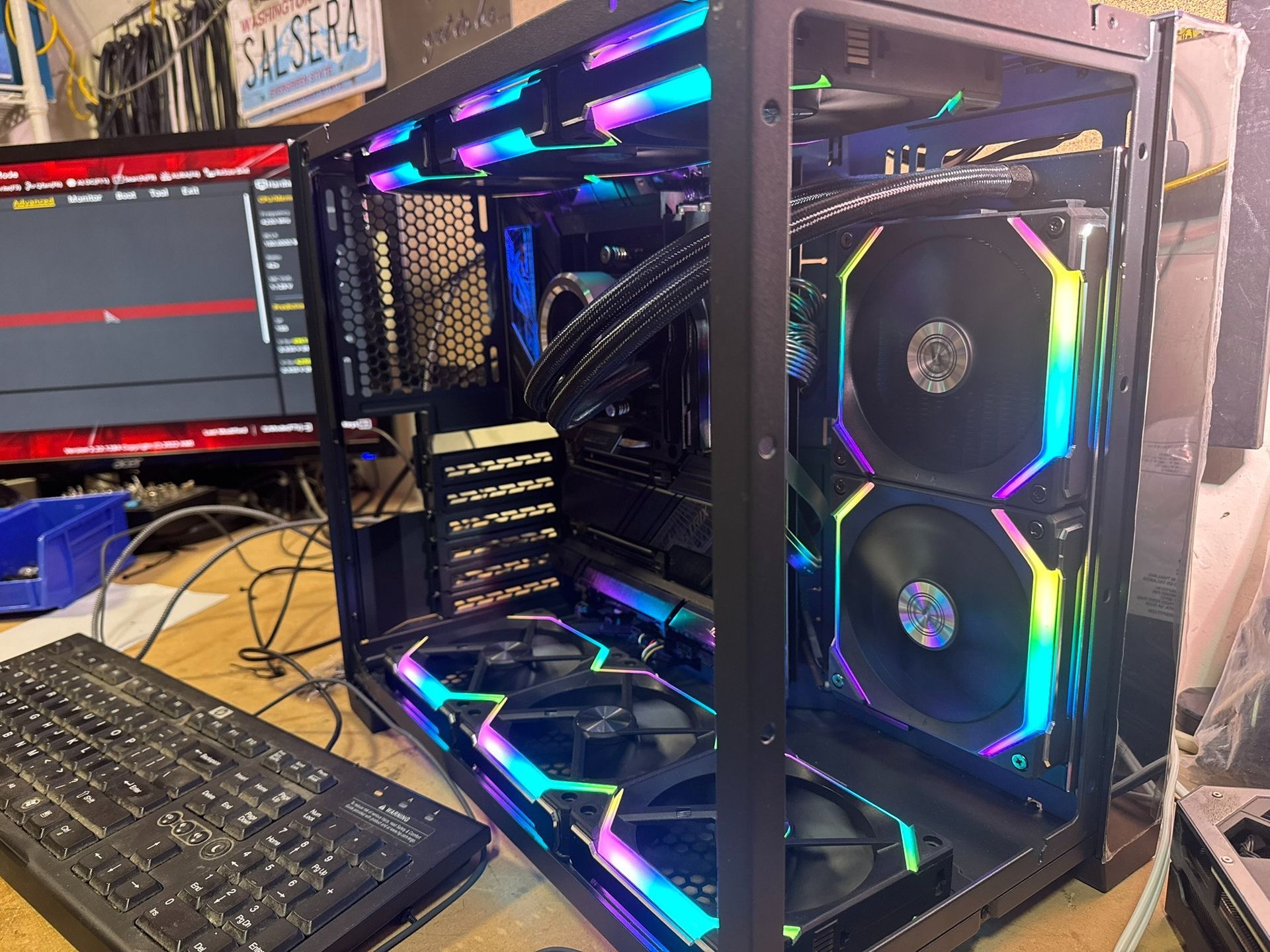 RGB-lit custom gaming PC on a desk beside a monitor and keyboard, with side panels open and visible fans.