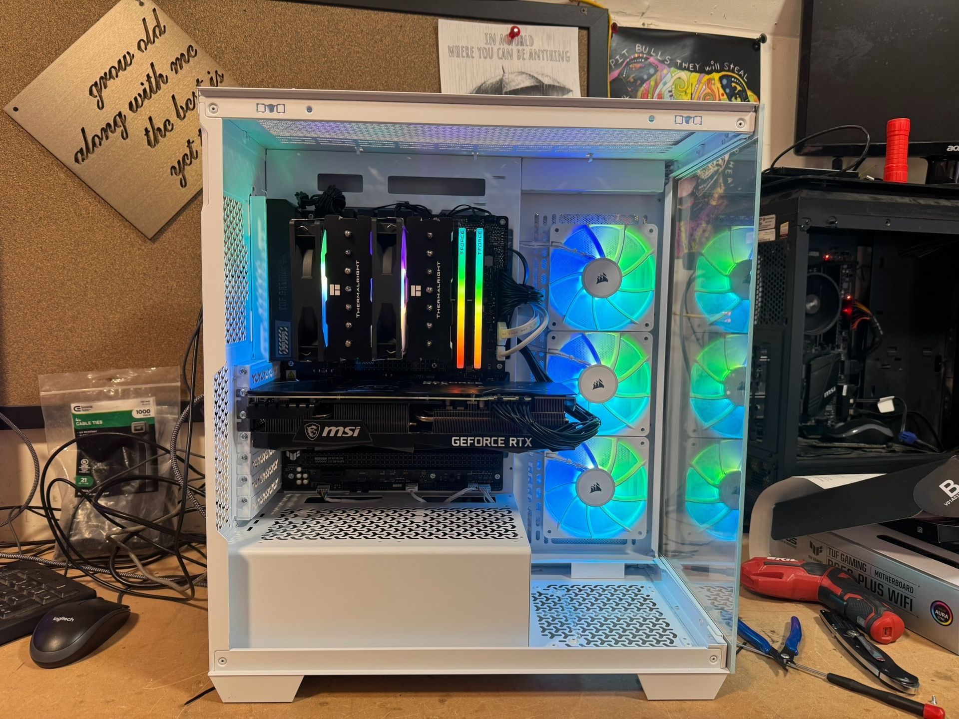 Open white PC case with RGB-lit components and front fans on a workbench.