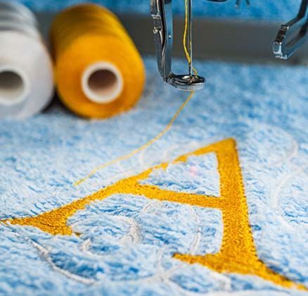 A alphabet design on towel in hoop of embroidery machine
