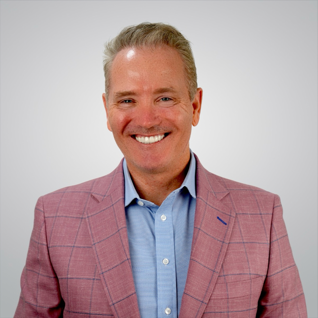 A man and a woman are sitting on a dock overlooking a lake.