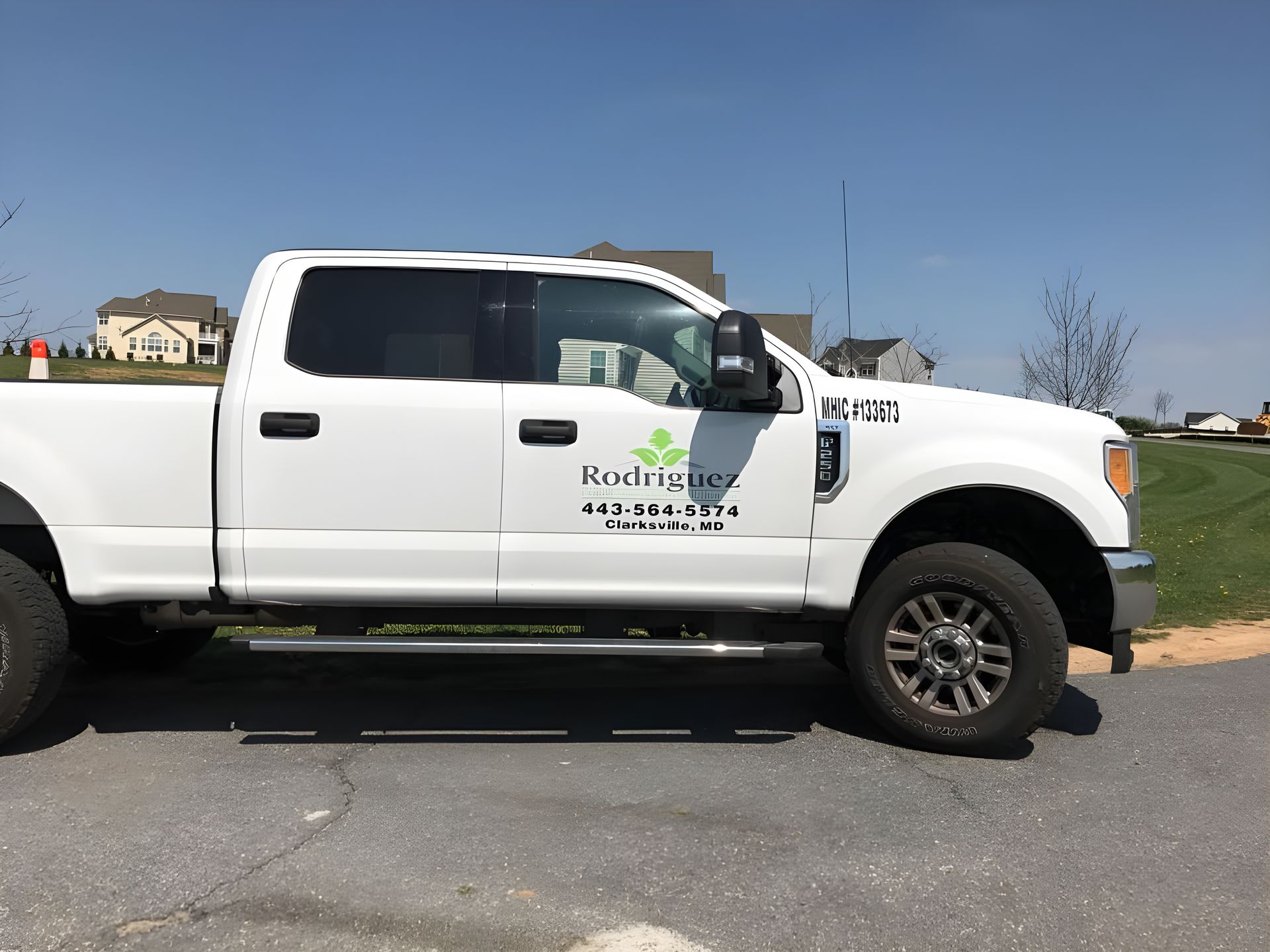 White pickup truck with company logo parked on a road under a clear sky