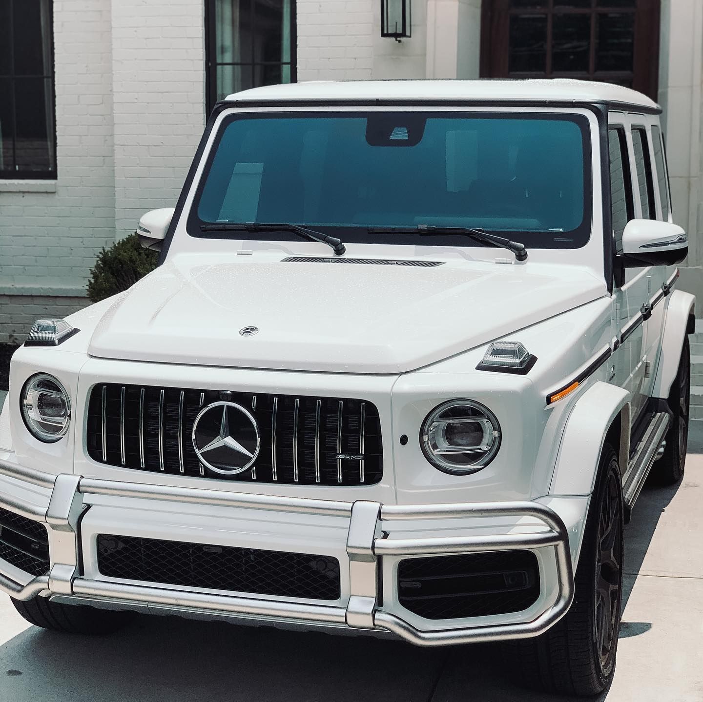 A white Mercedes-Benz G-Class SUV parked in front of a building.
