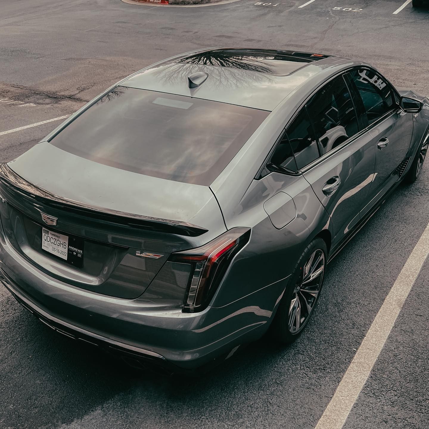 A high-angle view of a grey Cadillac CT5 sedan parked in an asphalt lot.