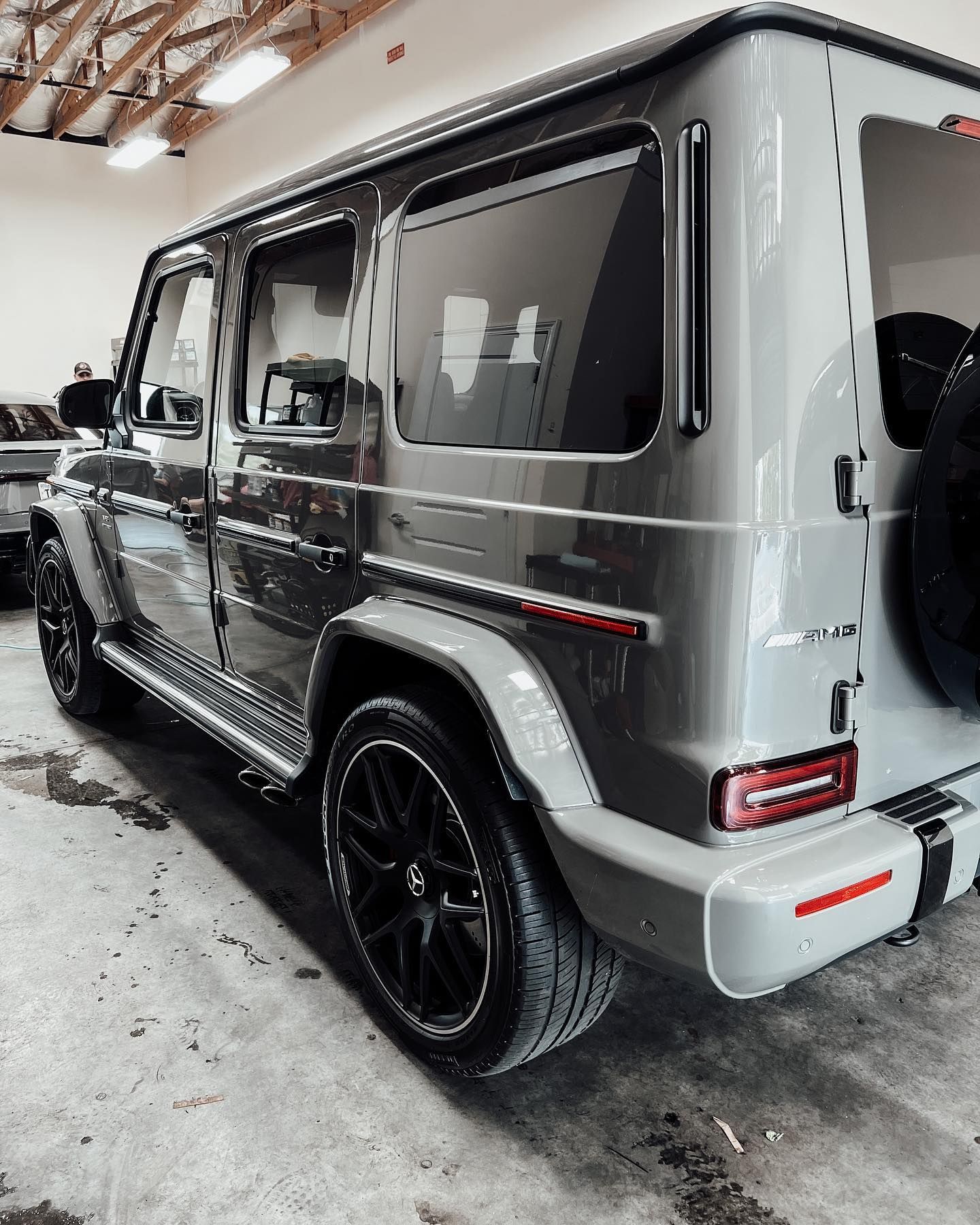 A light gray Mercedes-Benz G-Wagon parked in a bright, indoor garage with a concrete floor.