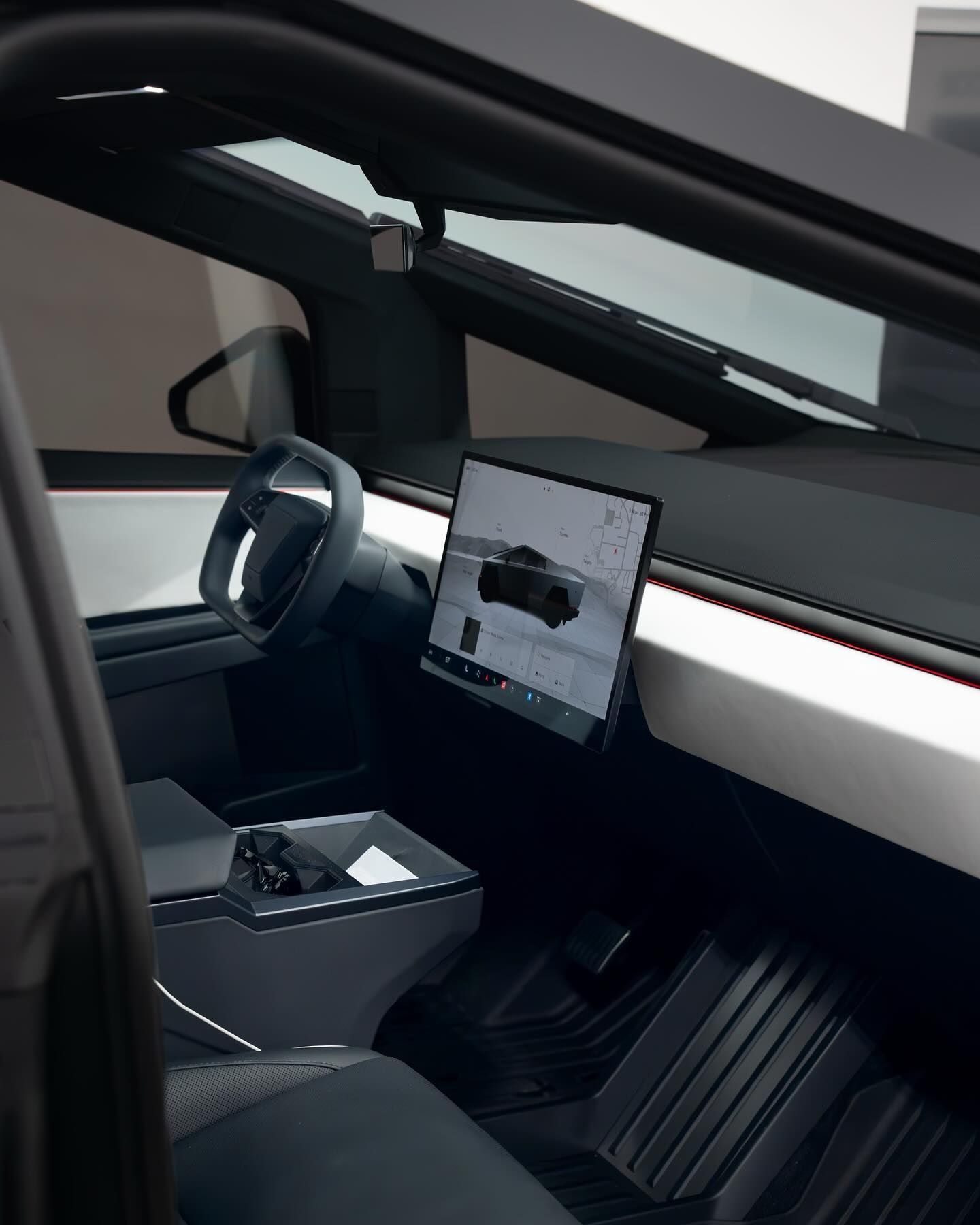 Minimalist interior of a Tesla Cybertruck with a digital display, steering wheel, and geometric dashboard design.