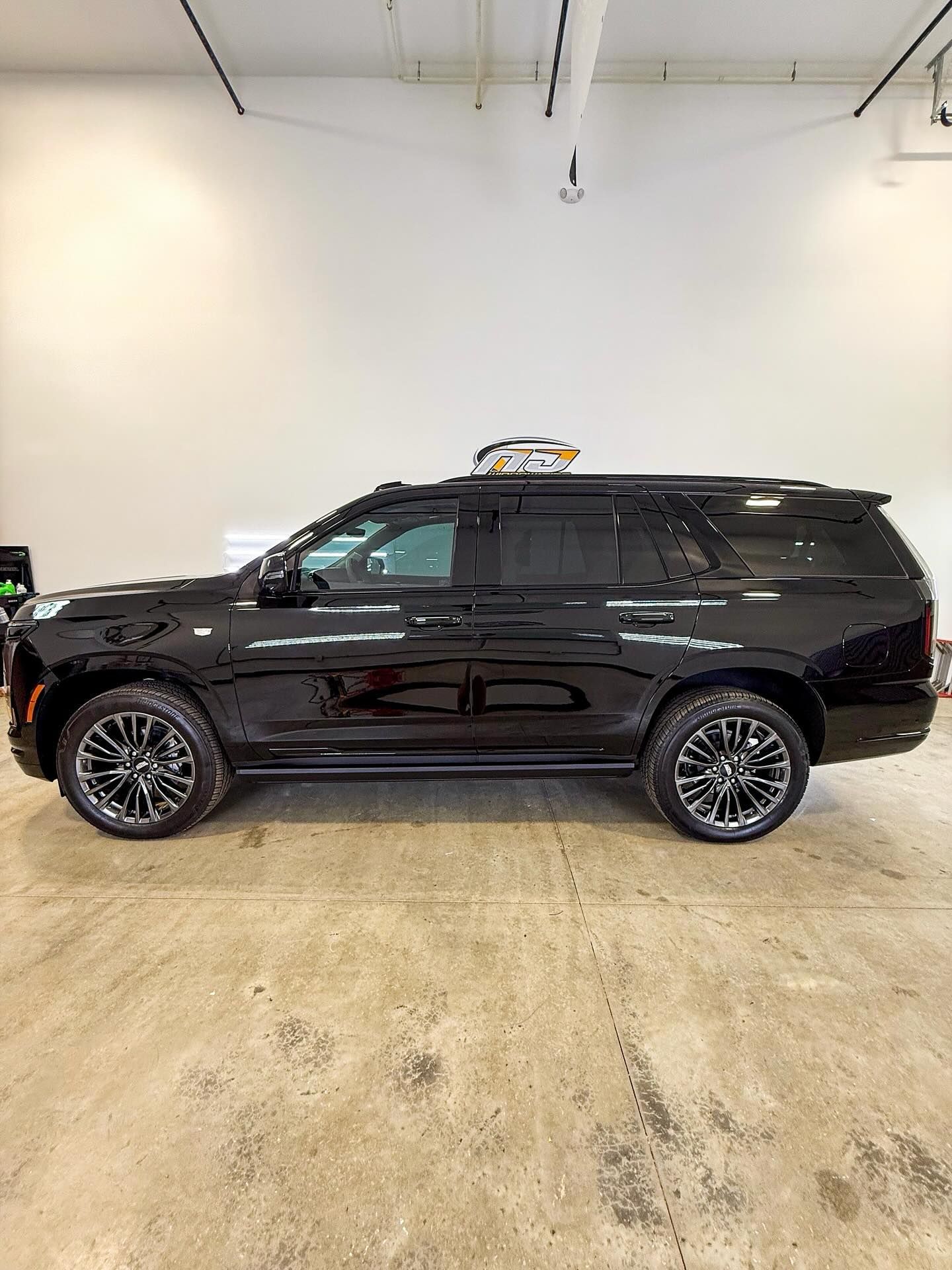 Side profile of a black SUV parked inside a bright, industrial-style garage.