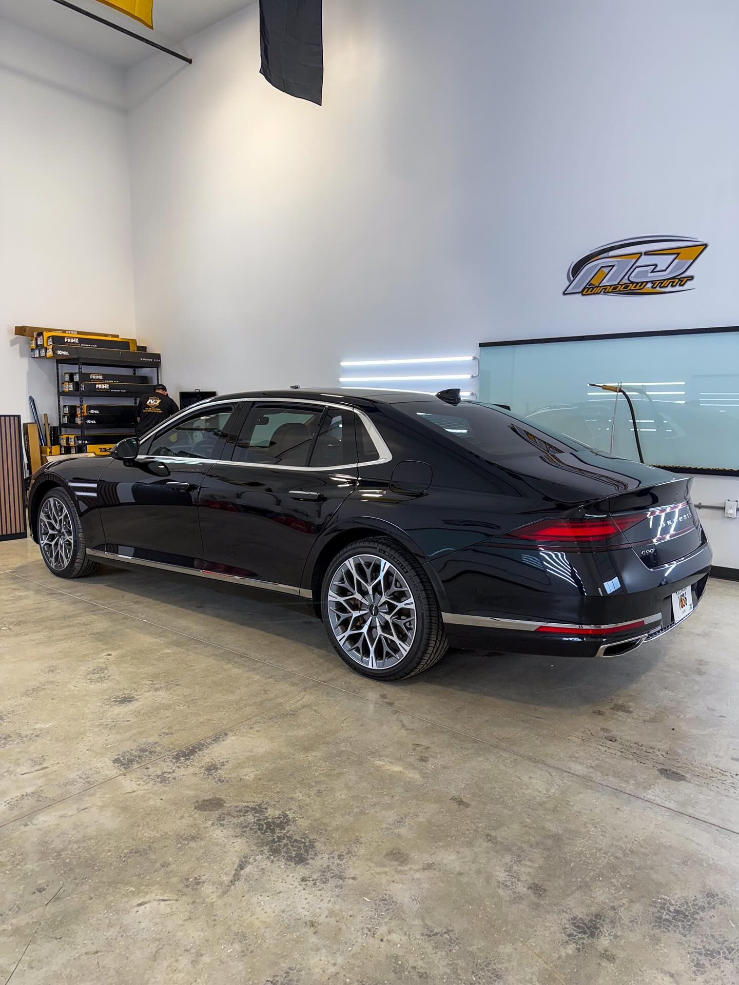 A black Bentley sedan parked inside a brightly lit garage with concrete floors.
