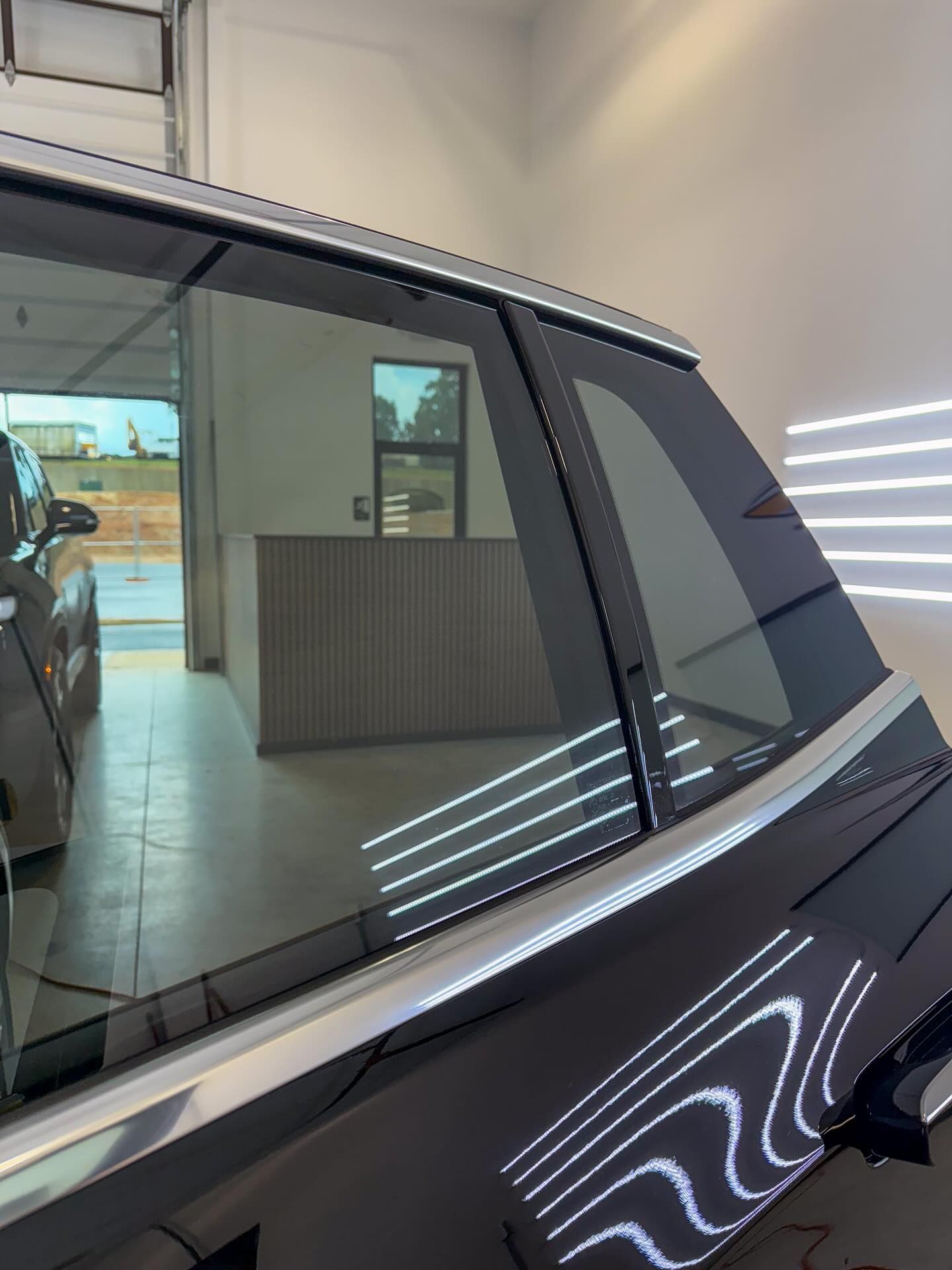 Dark tinted windows on a grey car parked inside a brightly lit garage.