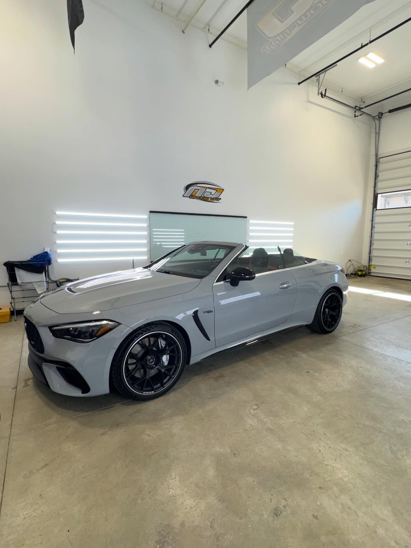 A gray Mercedes-Benz convertible parked inside a well-lit, industrial-style garage.
