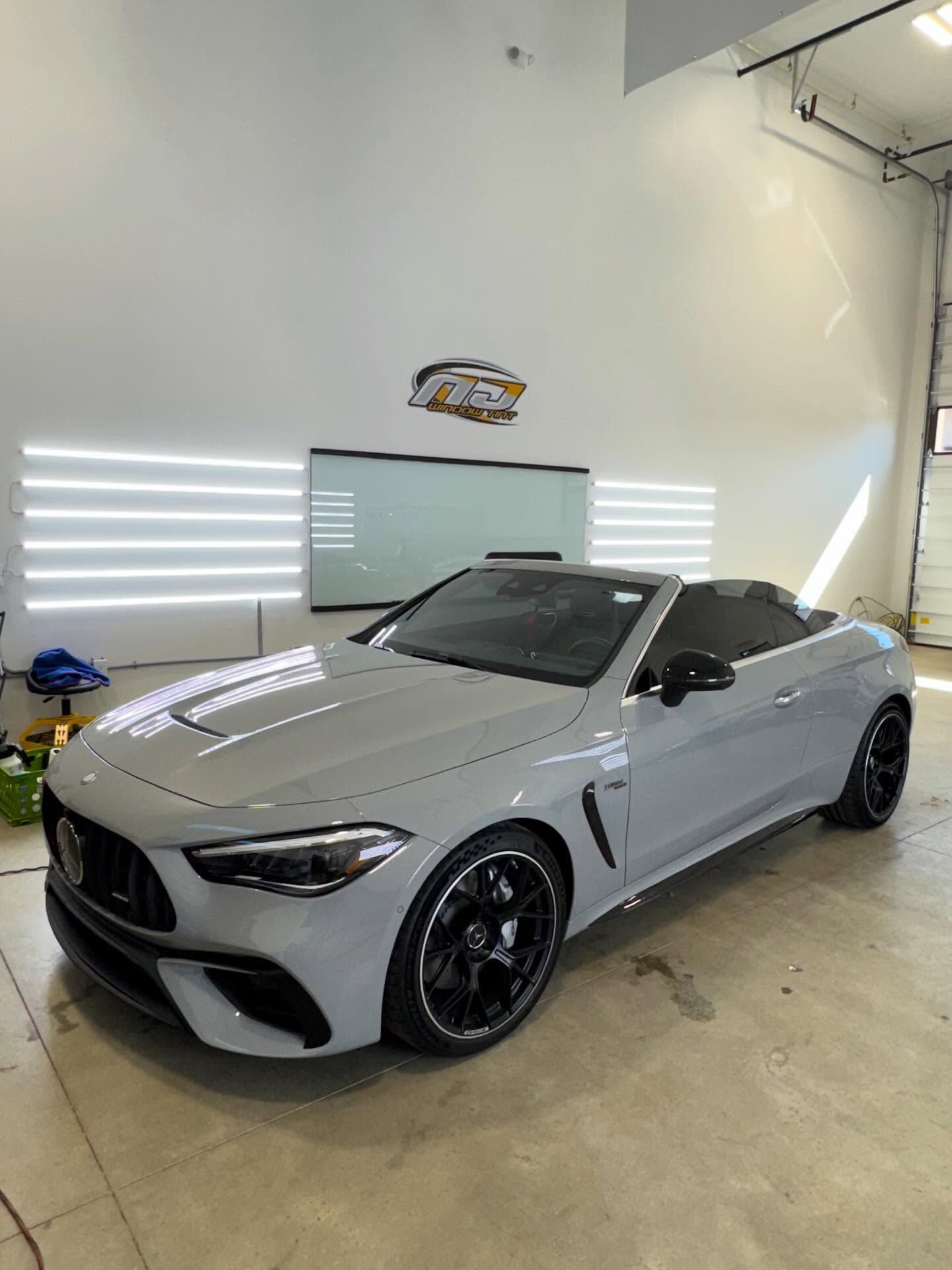 A gray Mercedes-AMG CLE convertible parked inside a professional automotive detailing garage.
