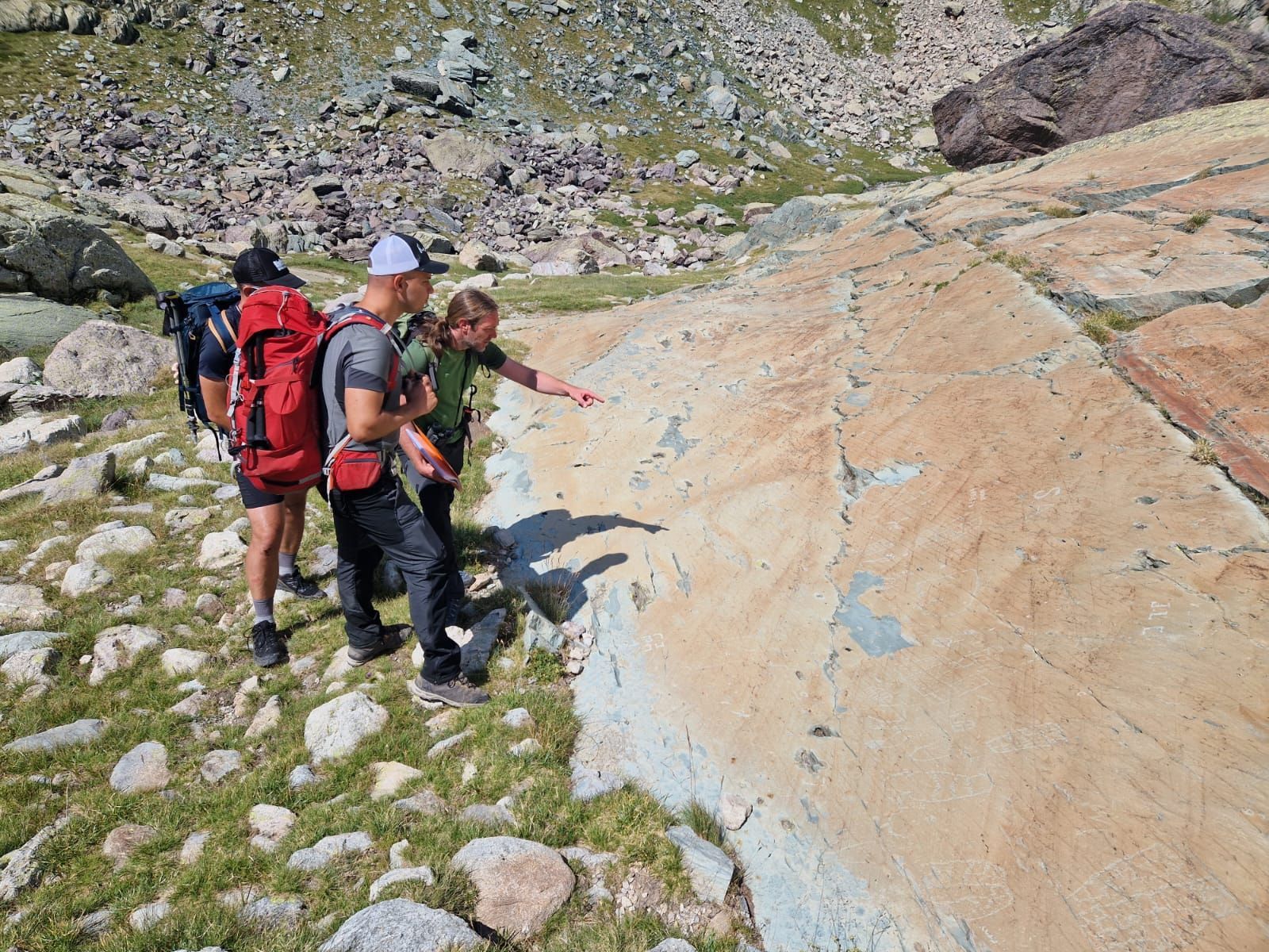 Des personnes devant une dalle rocheuse gravée