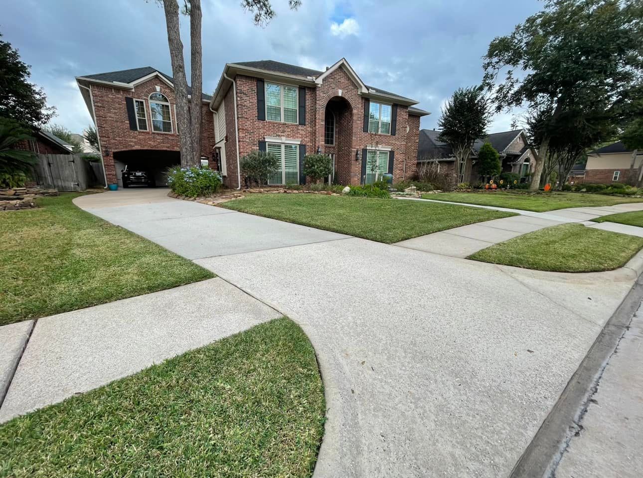 A large brick house with a concrete walkway leading to it