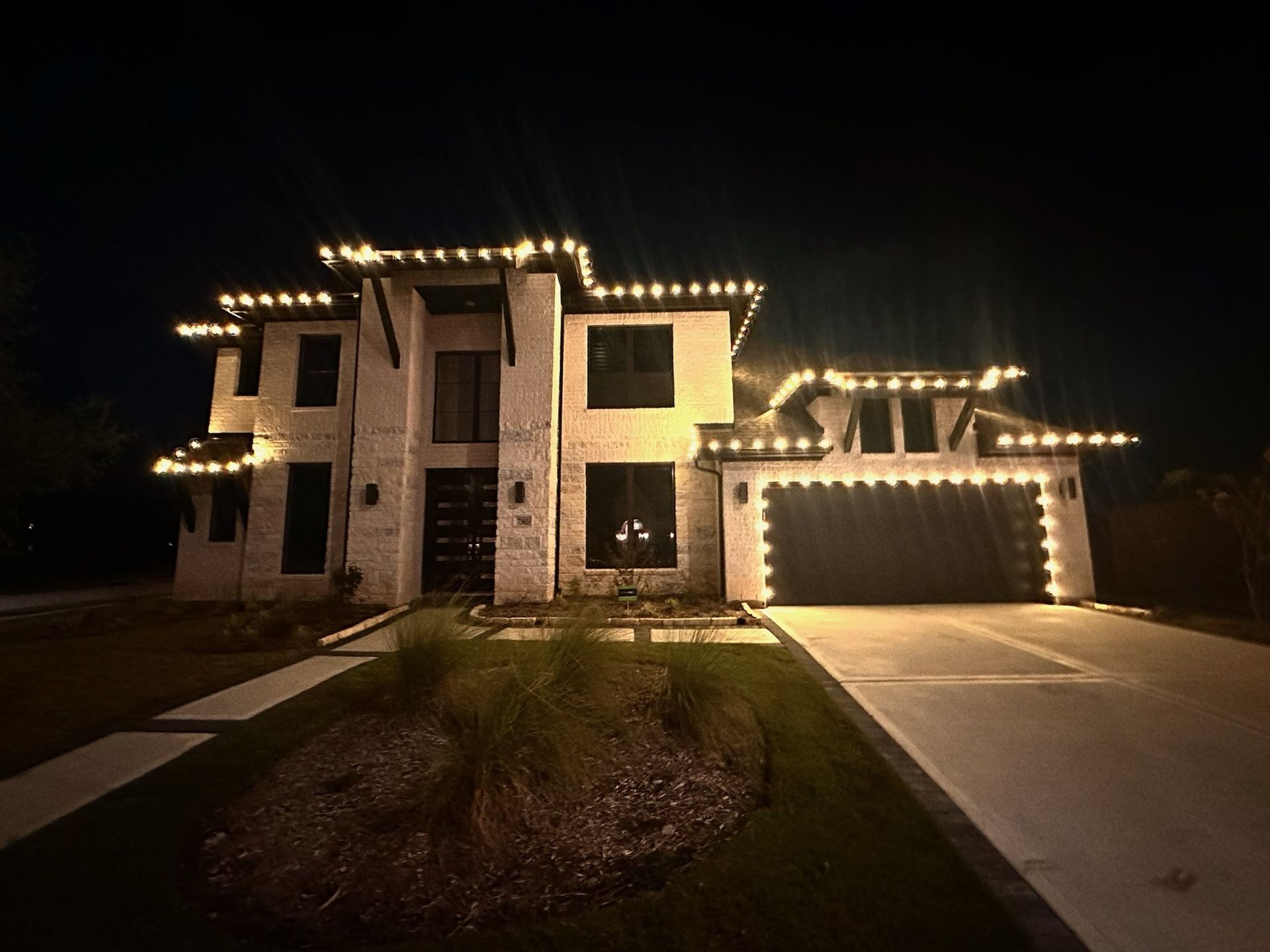 A large house is lit up with christmas lights at night.