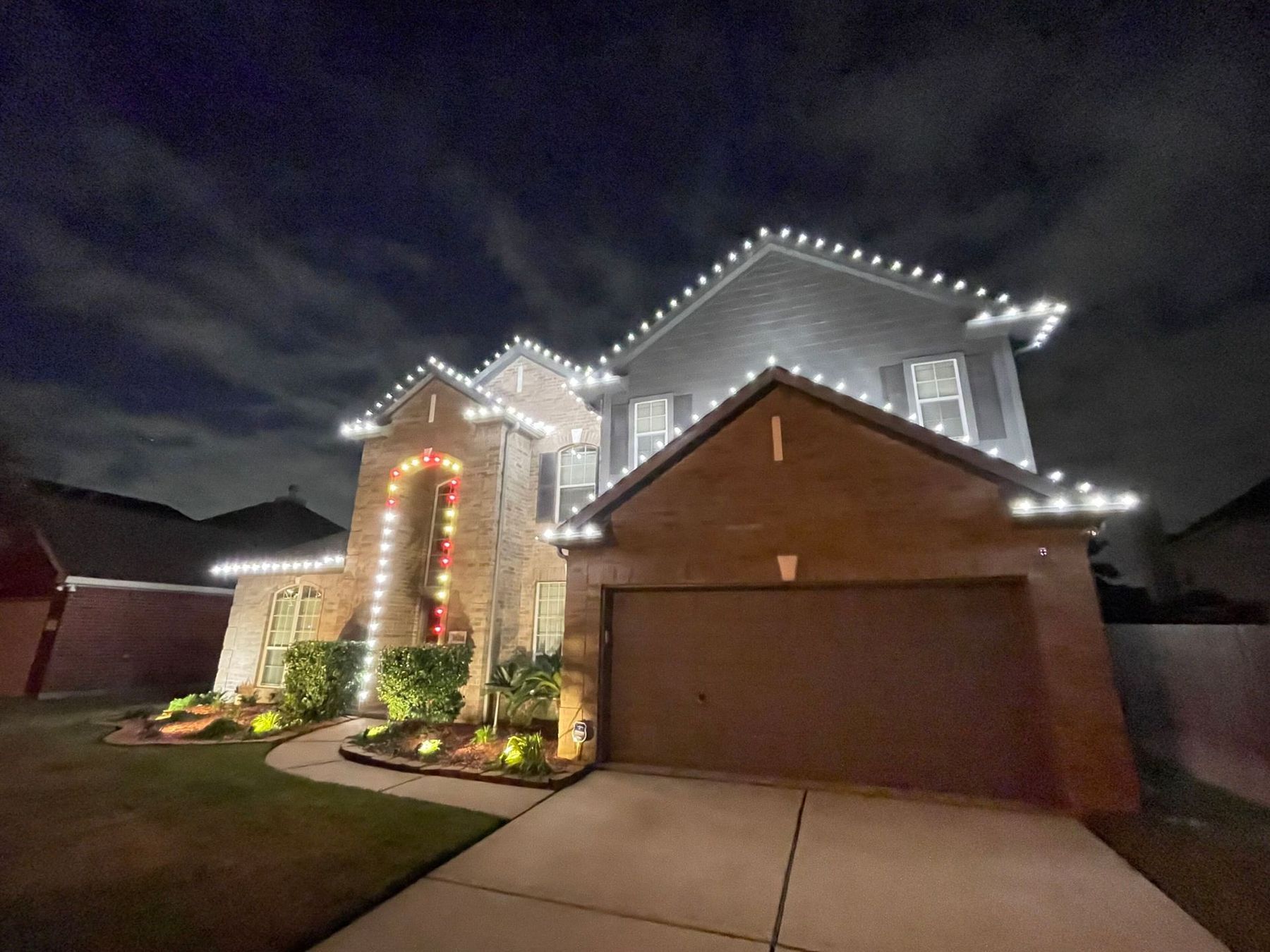 A large house is decorated with christmas lights at night.