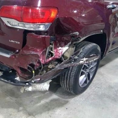 Damaged red SUV, rear quarter panel dented and bumper crumpled. Tire exposed. | Jacobson Body Shop