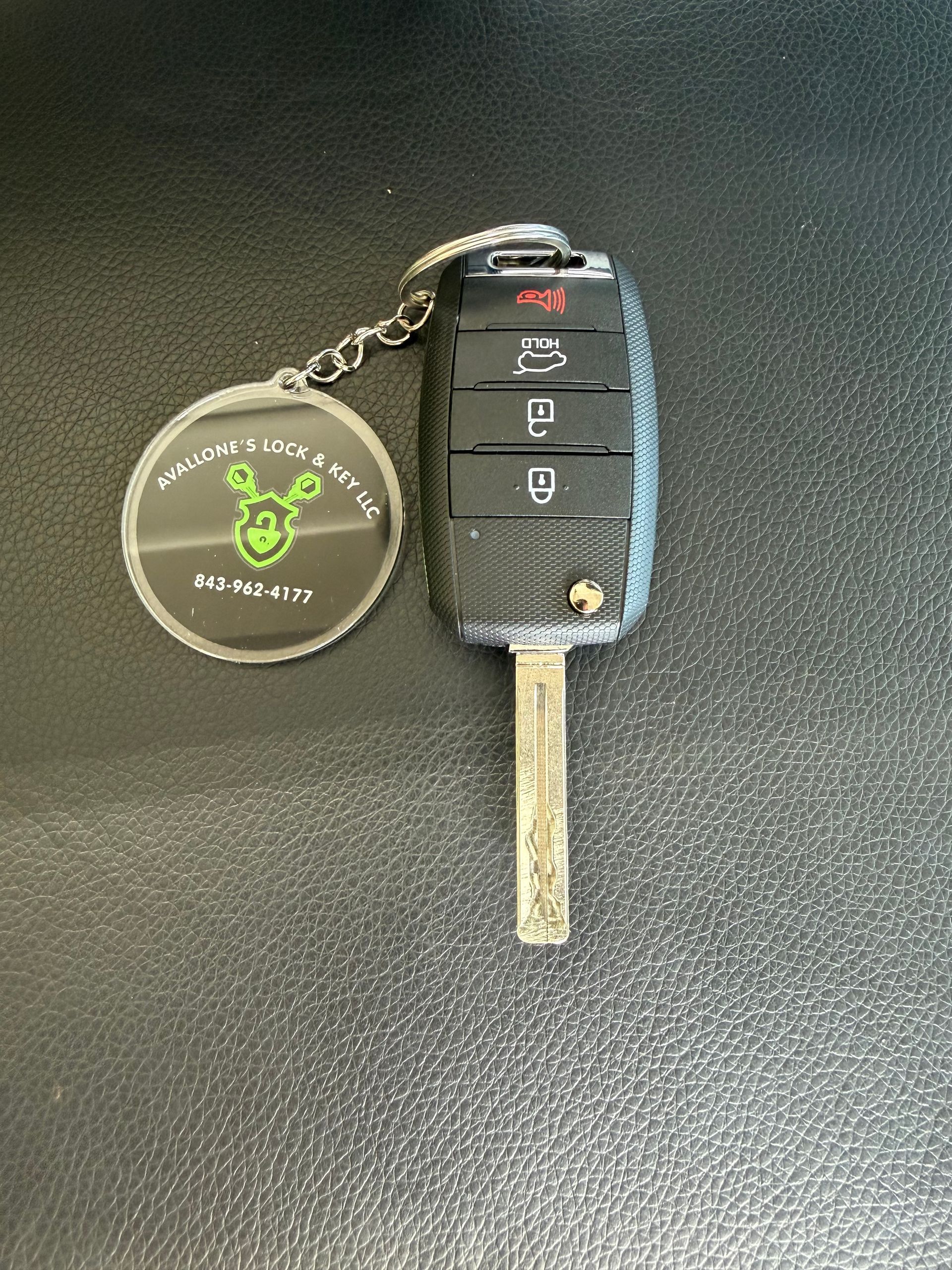 A car key and remote control are on a white surface.
