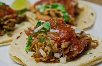A close up of a taco with meat and sauce on a plate.