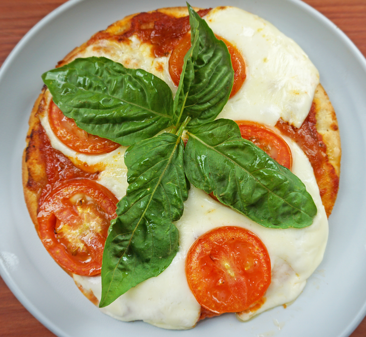 A pizza with tomatoes and basil on a plate