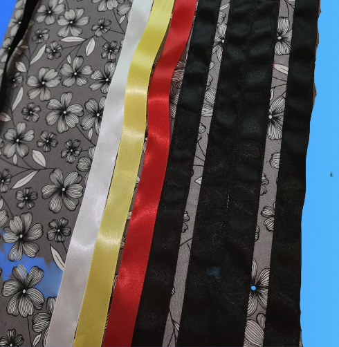 Gray floral fabric with ribbons in white, yellow, red, and black.
