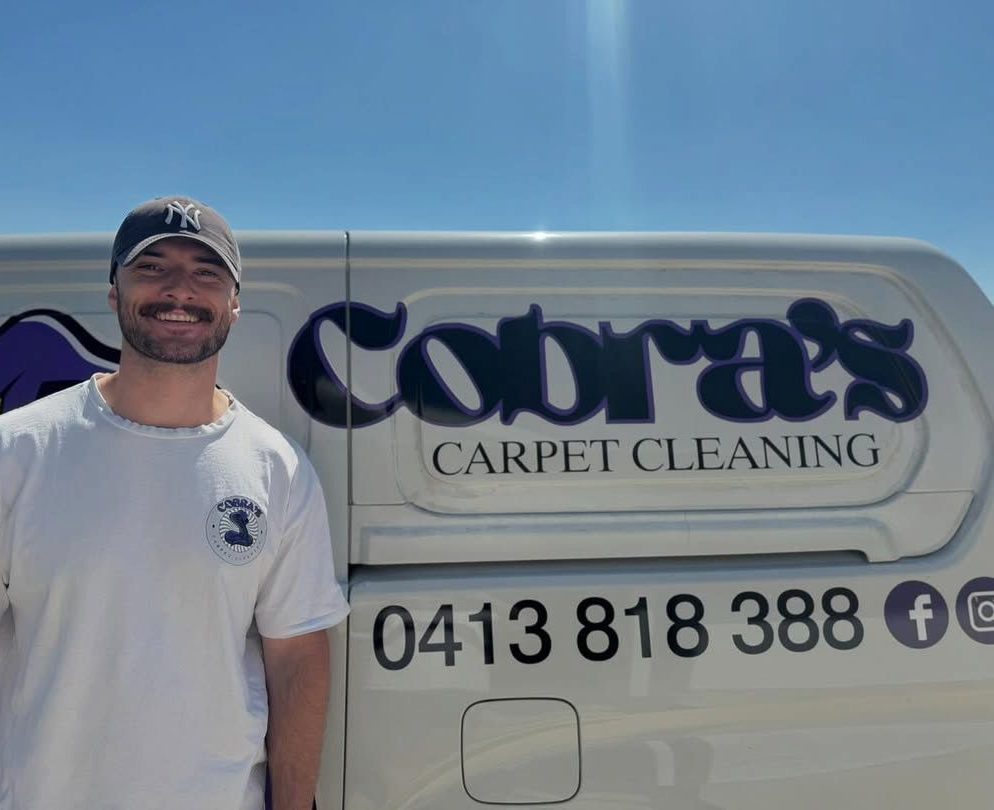 A Person Wearing a Cap and T-shirt Stands in Front of a White Van Branded — Cobra's Carpet Cleaning in Junee, NSW