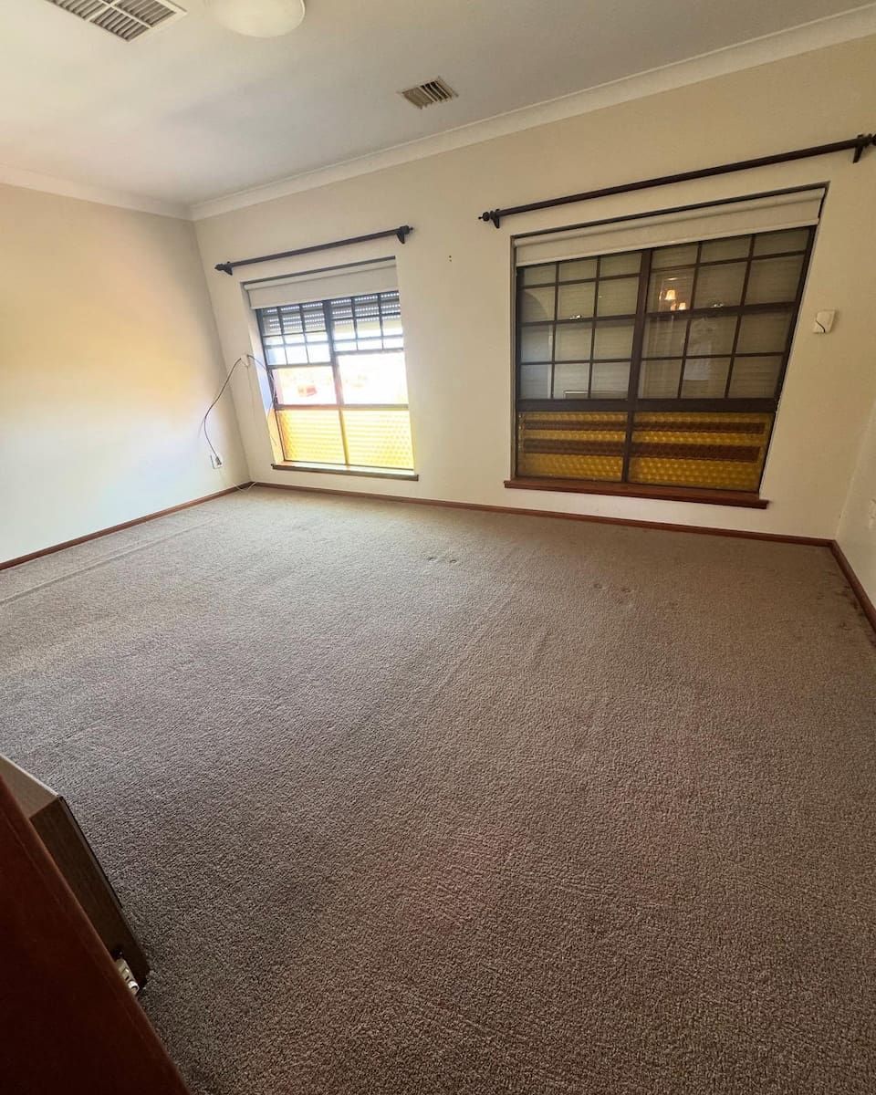 A Spacious, Empty Room With Light Walls, Beige Carpet, and Two Large Windows — Cobra's Carpet Cleaning in Cootamundra, NSW