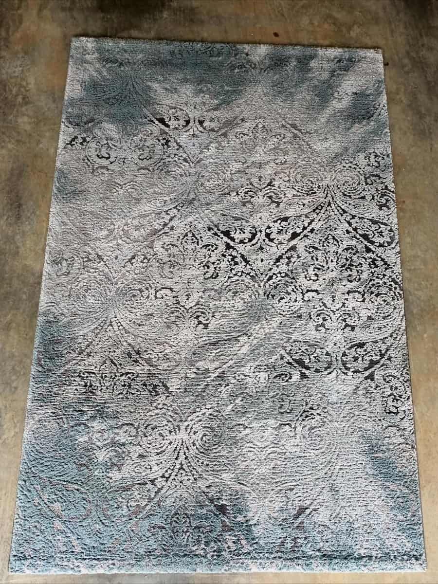 A rectangular rug with an intricate, distressed grey and charcoal pattern laying on a concrete floor  — Cobra's Carpet Cleaning in Junee, NSW