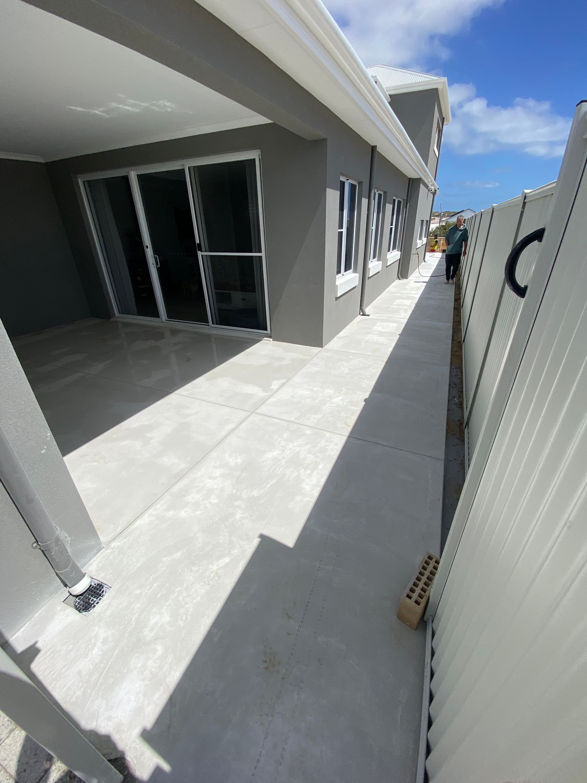 Grey concrete patio and walkway down the side of the house
