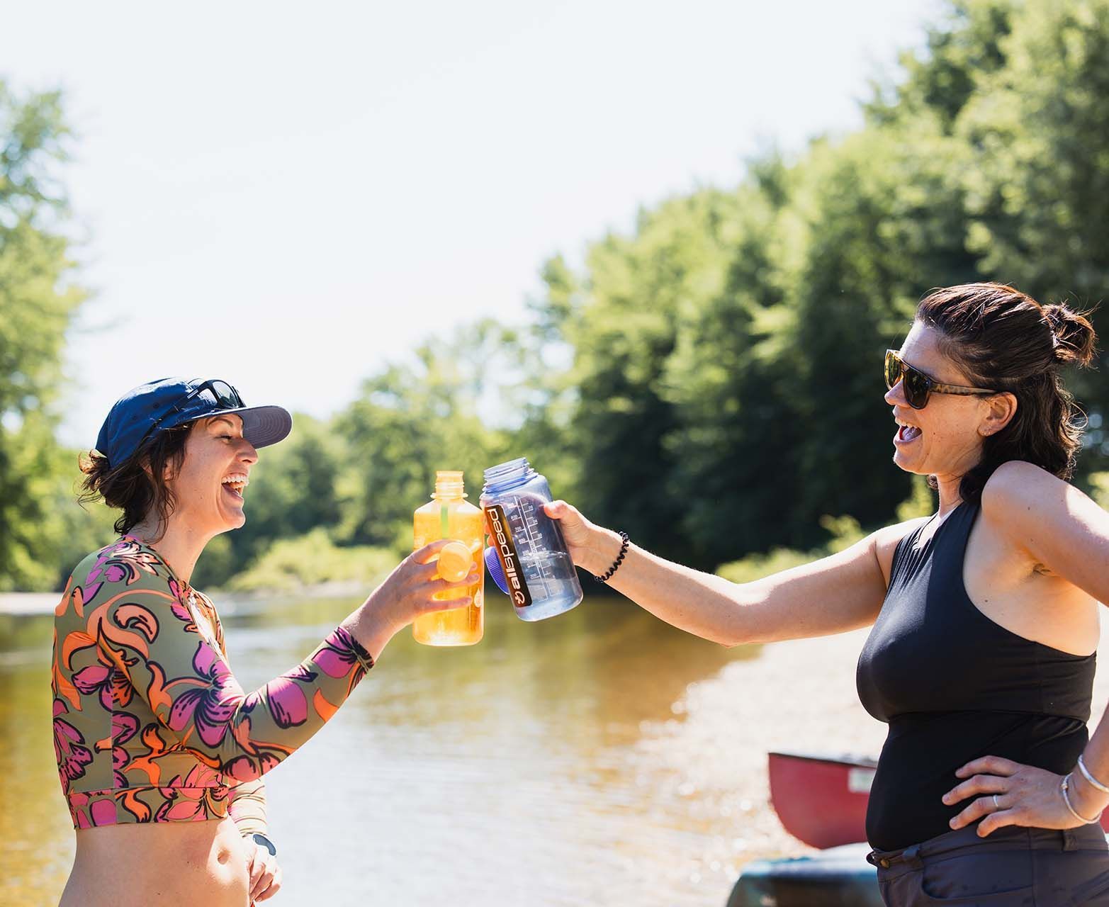 Two Women Are Toasting with Drinks in Front of A River