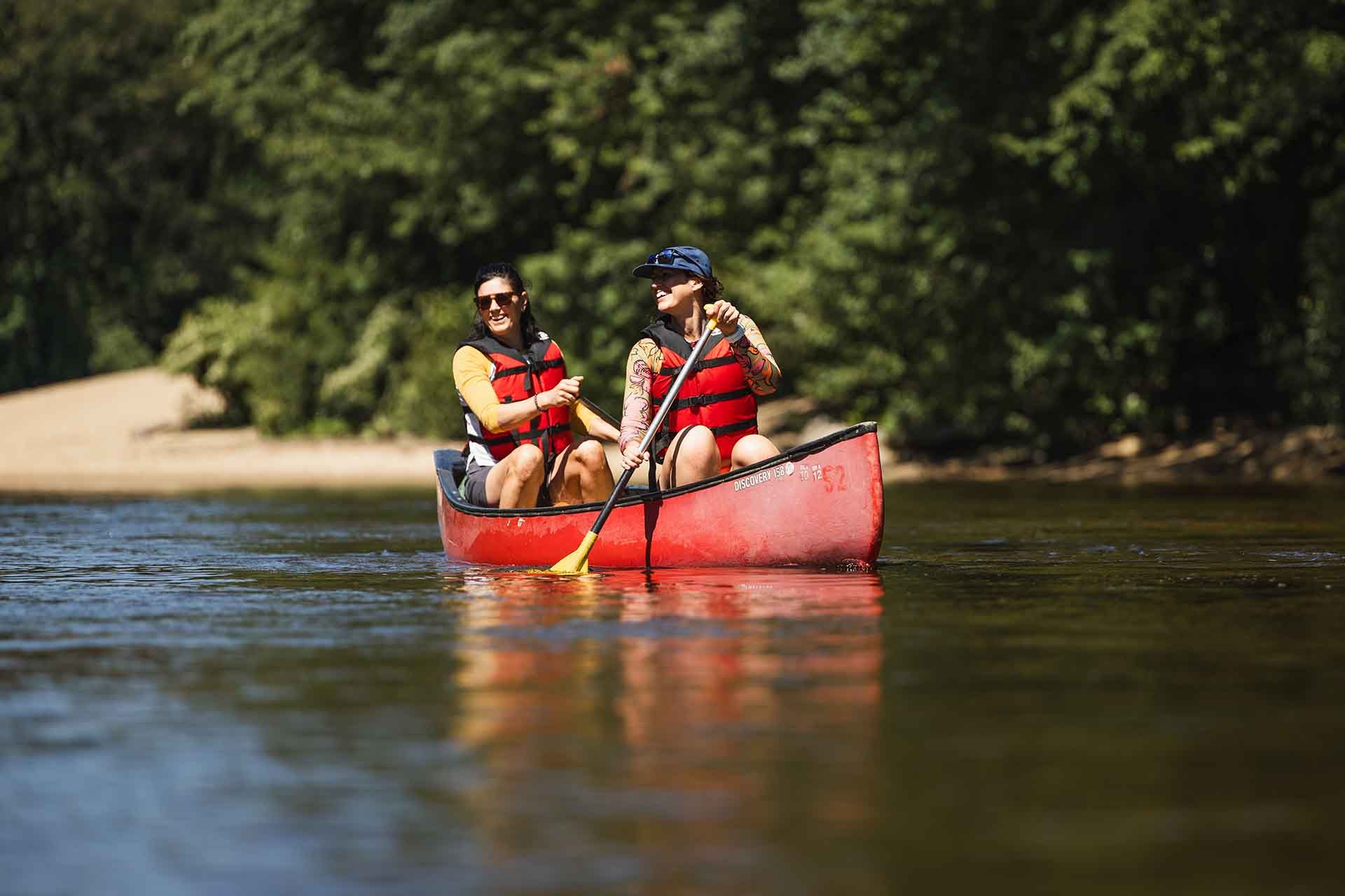 two woman canoeing down a river