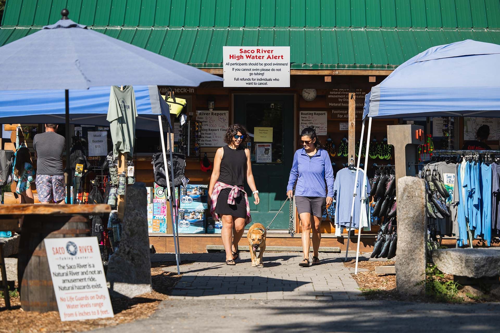 two women and dog walking out of river tubing store 