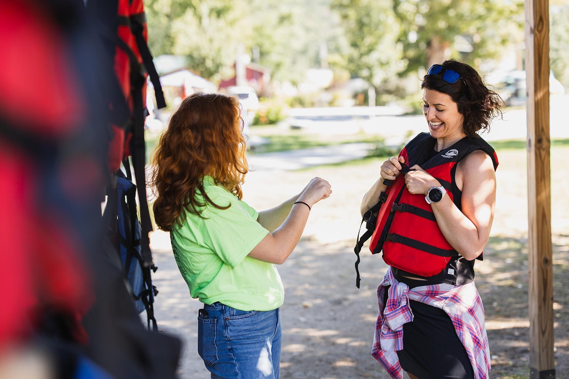 Two women are standing next to each other and one of them is wearing a life jacket.