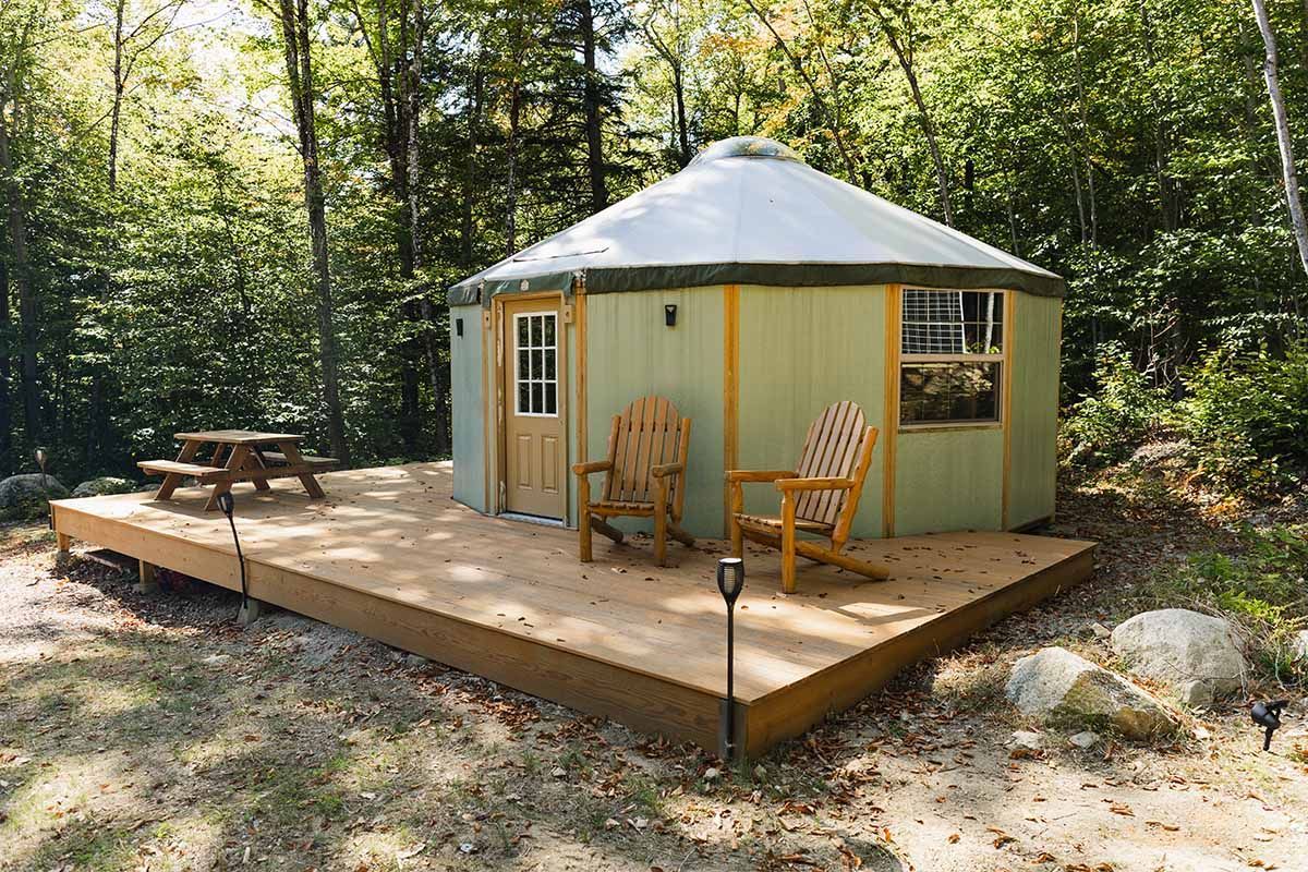 A Yurt Is Sitting on Top of A Wooden Deck in The Middle of A Forest