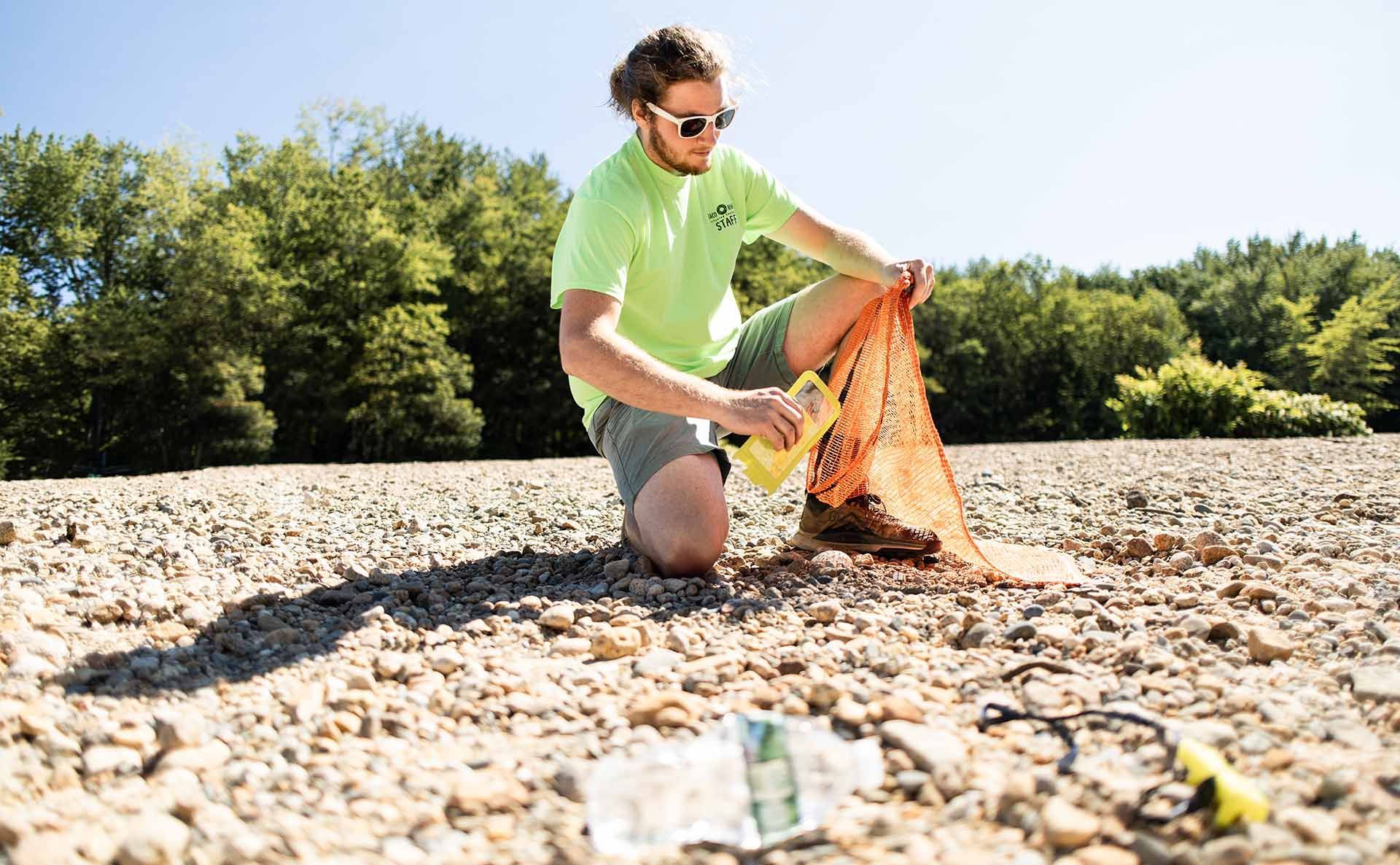 A man collecting plastic bottles from the sand