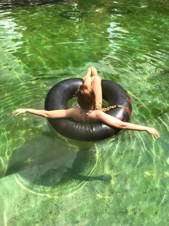 A woman is floating on a black inner tube in the water.