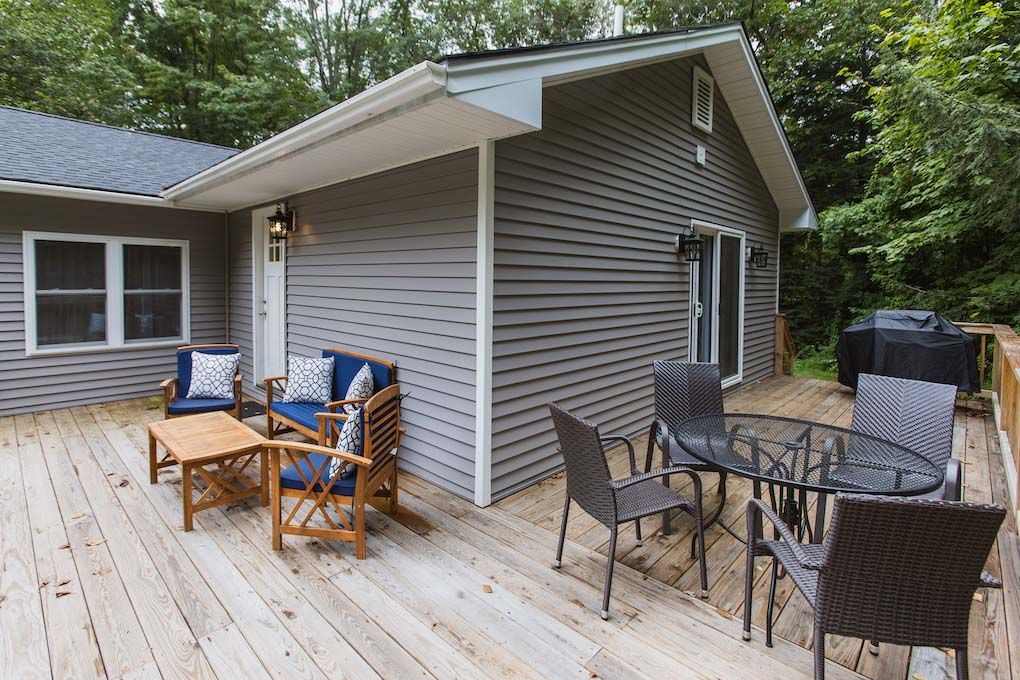 A Wooden Deck with A Table and Chairs in Front of A House