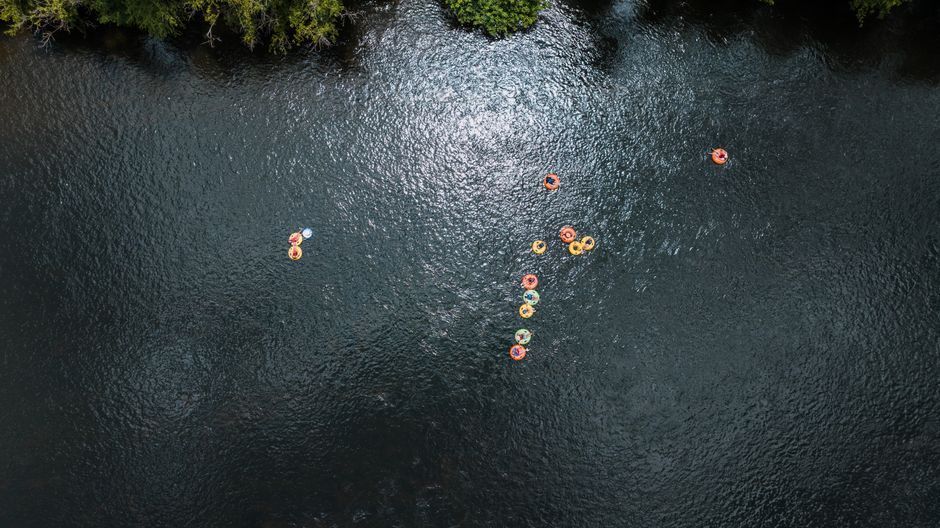 People floating on inner tubes down a calm river on a sunny day