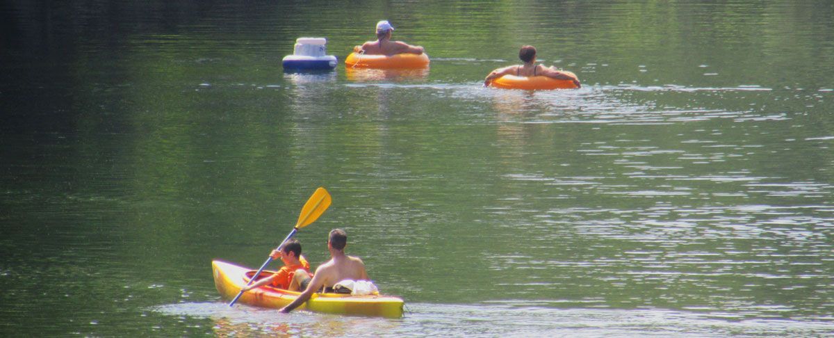 A group of people are rowing kayaks on a lake.