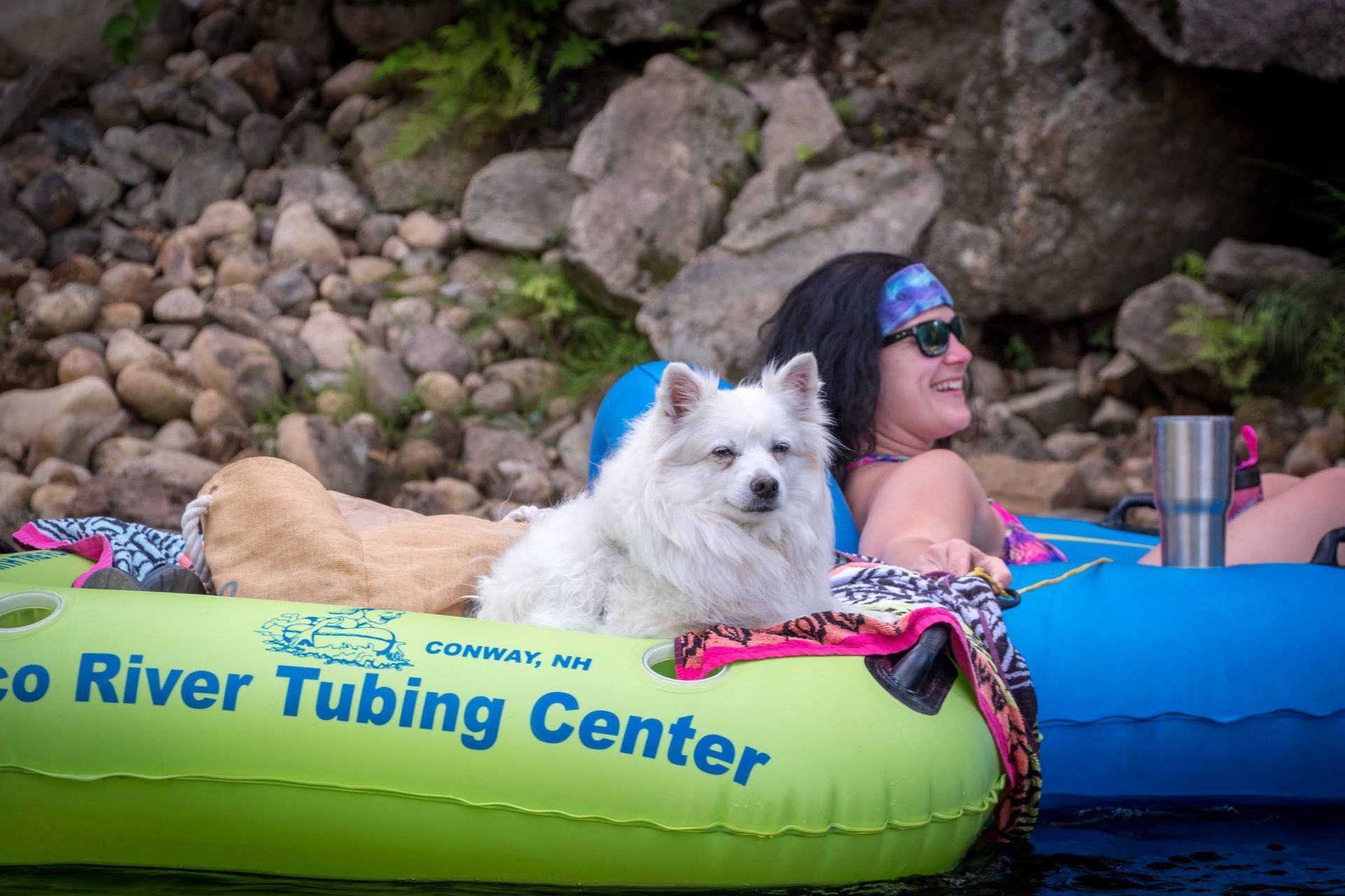 A woman and a dog are sitting on a tube in the water.