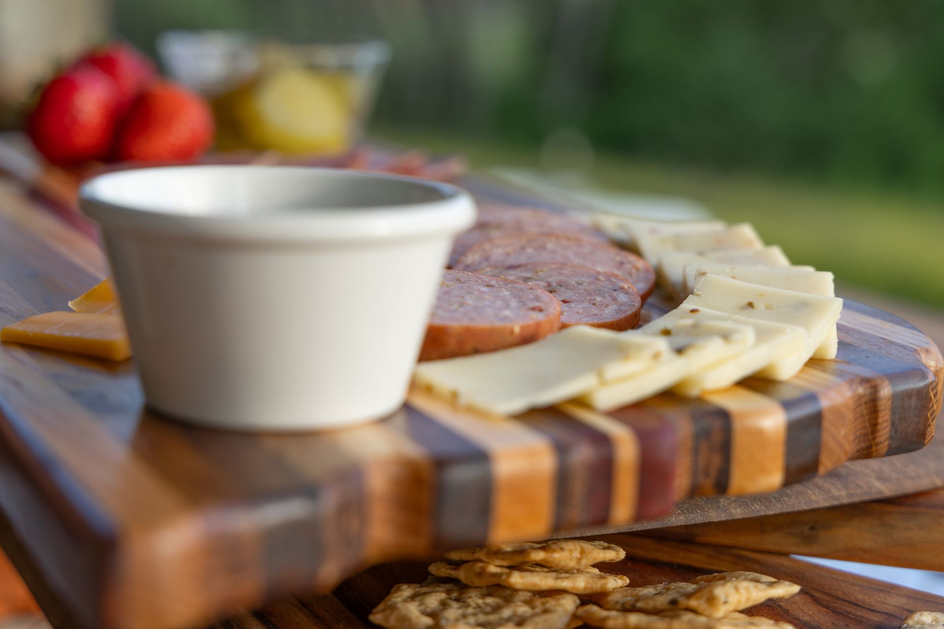Charcuterie board with cheeses, meats, dipping sauce, and crackers.