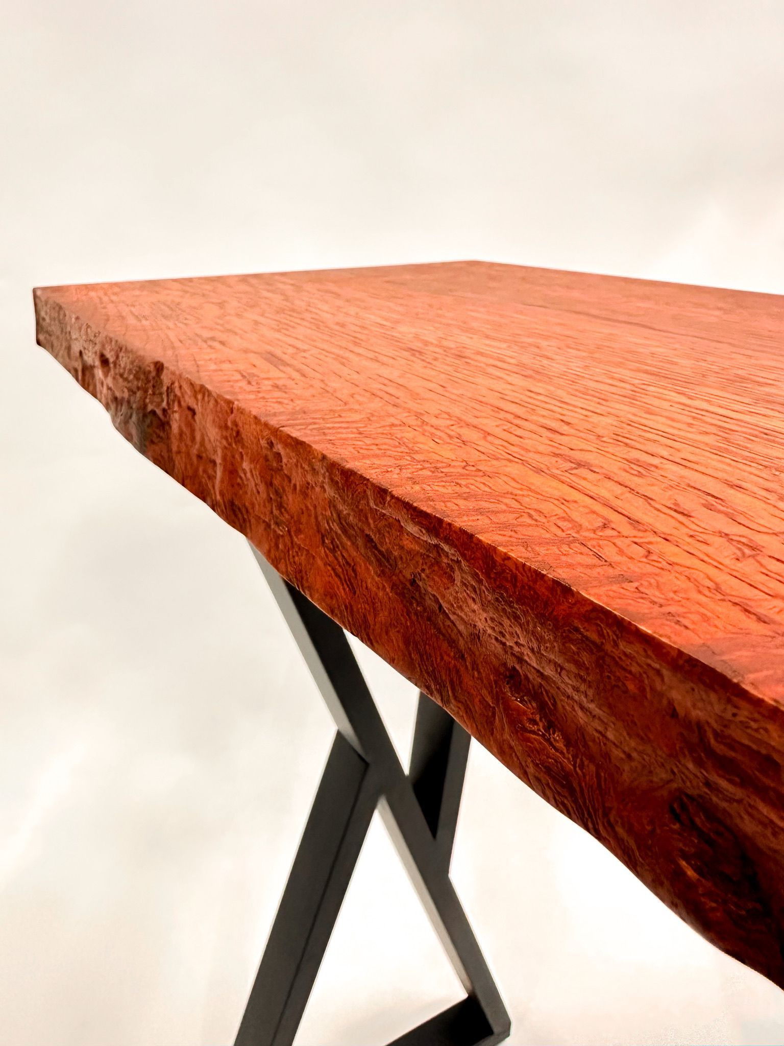 Red wood table with black metal legs against a white backdrop.