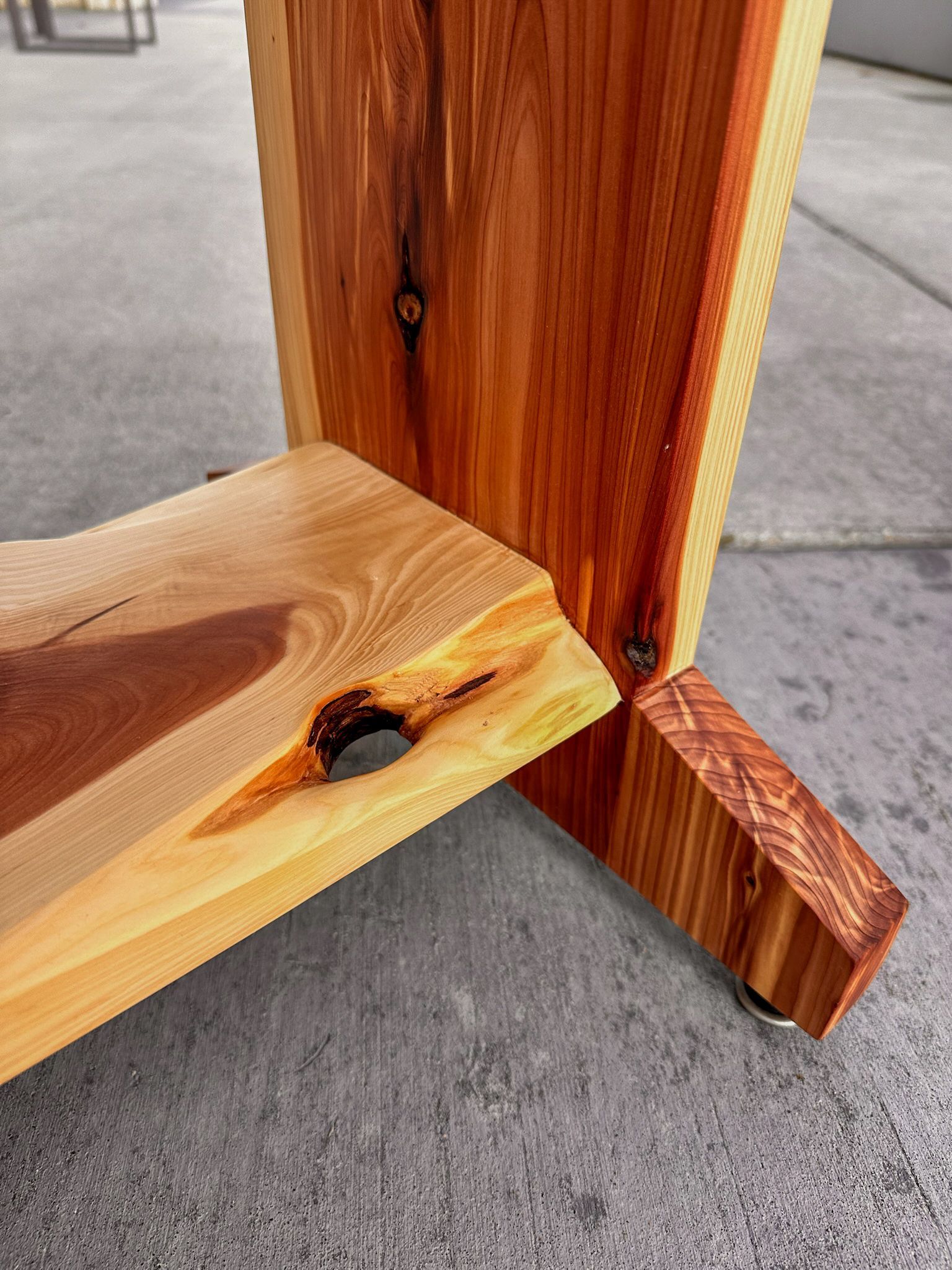 Wooden table leg detail, showing joinery, natural wood grain, and colors of red and blonde.