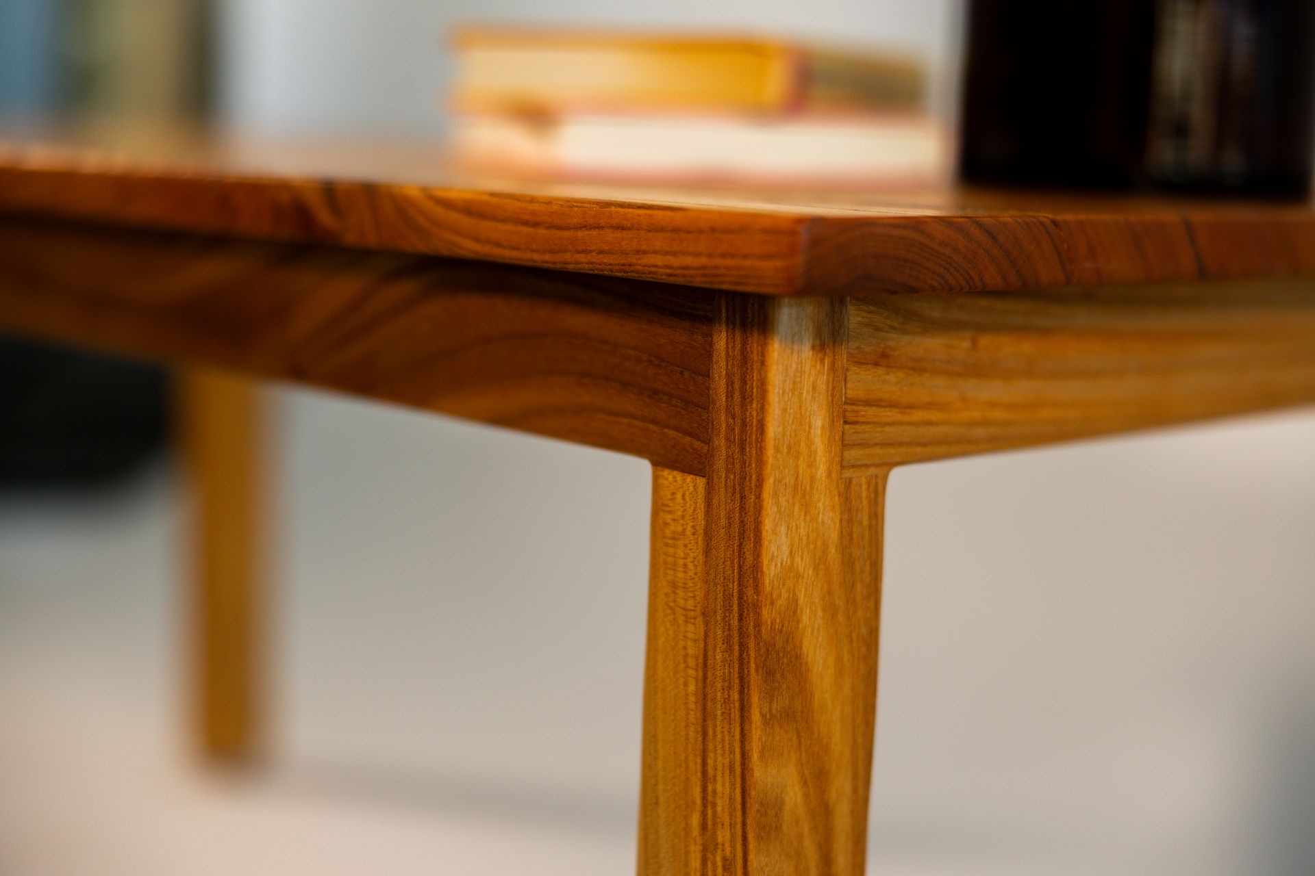 Close-up of a wooden coffee table with light brown legs and a darker brown top.