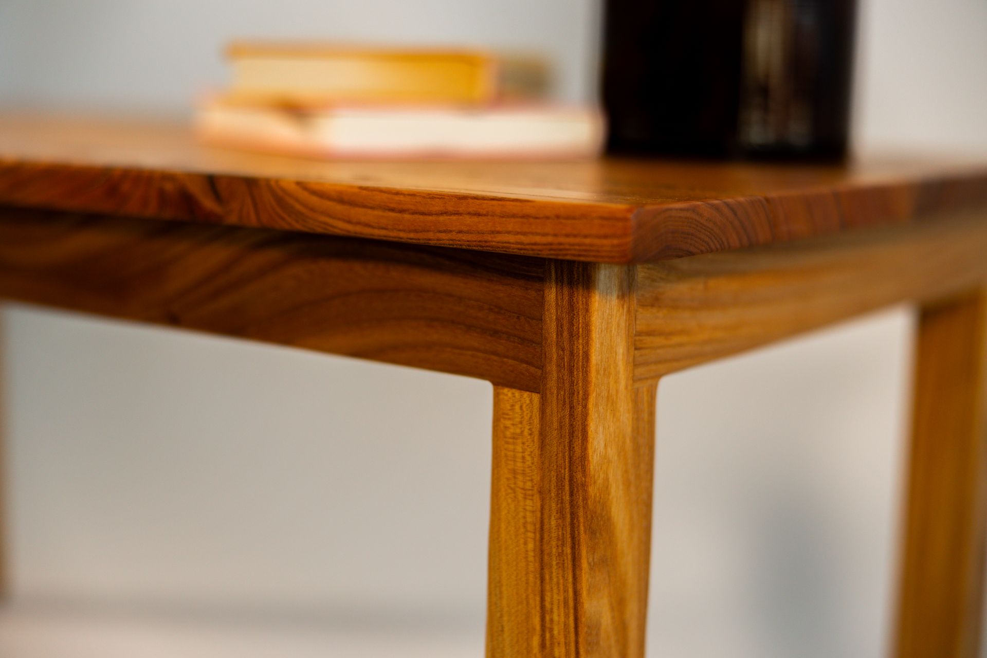 Wooden table with books and a dark object on top.