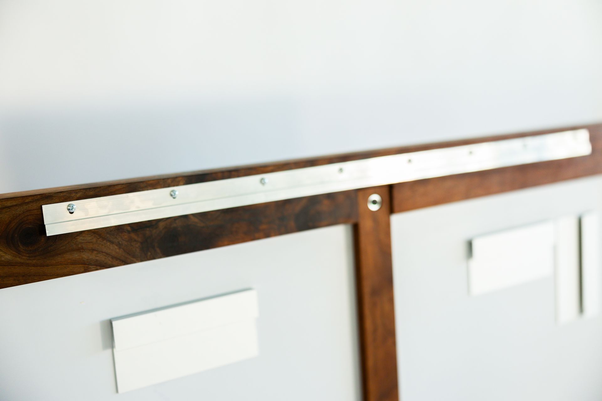 Wooden-framed panels with silver metal strip at the top, white rectangles attached to the panels.