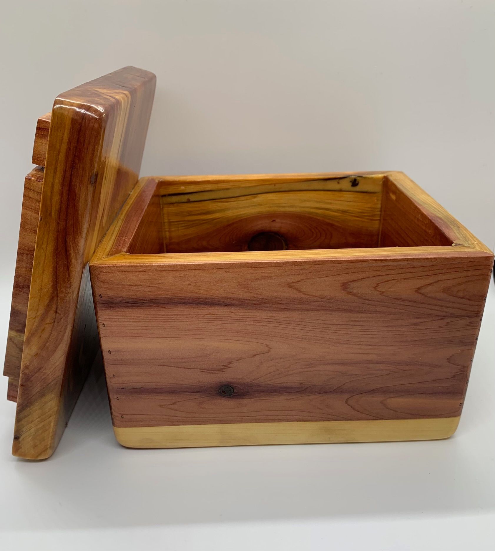 Wooden box, open lid reveals cedar interior, stained reddish-brown exterior, light-colored base.