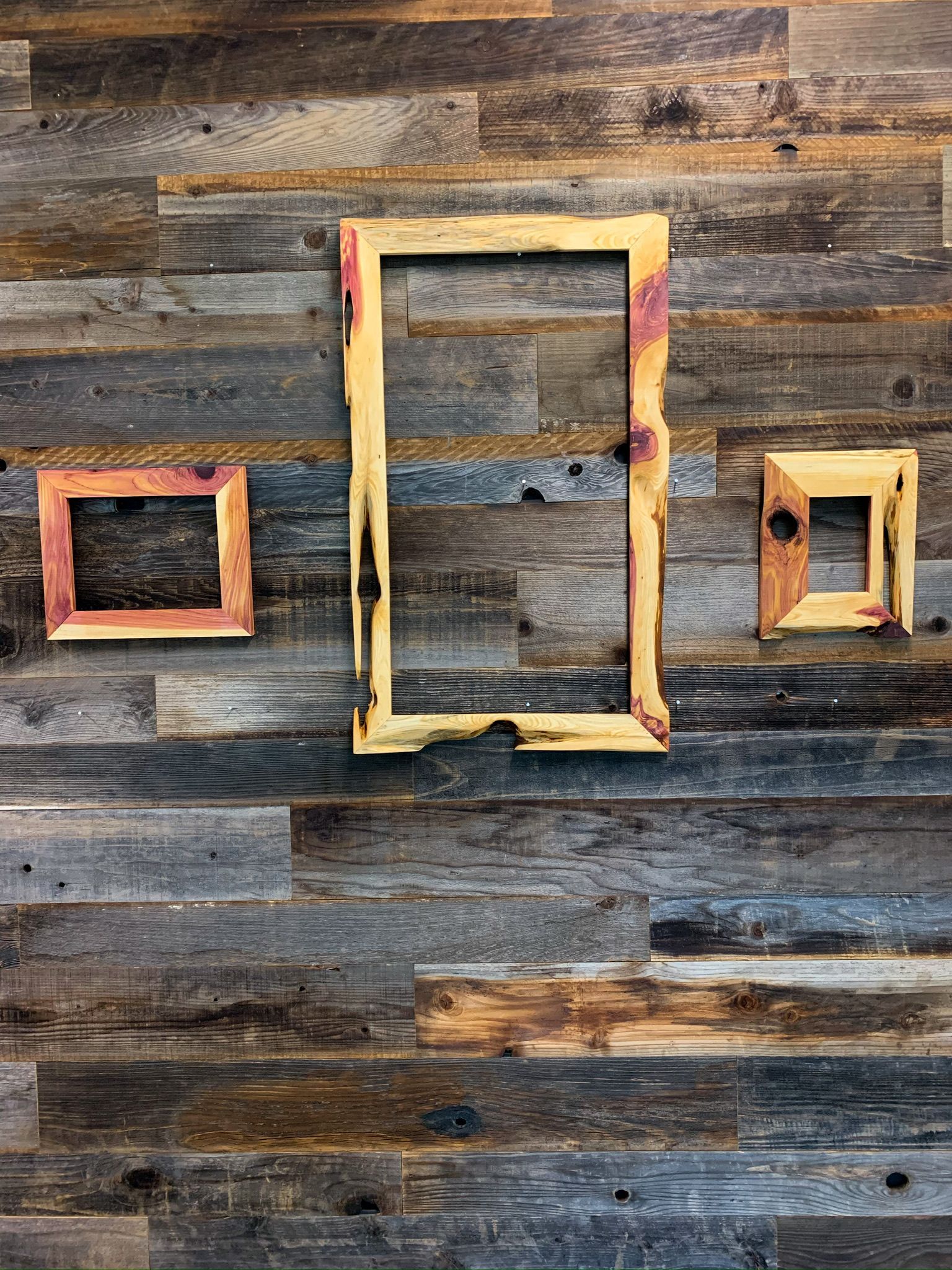 Three rustic wooden frames hanging on a weathered wooden wall.
